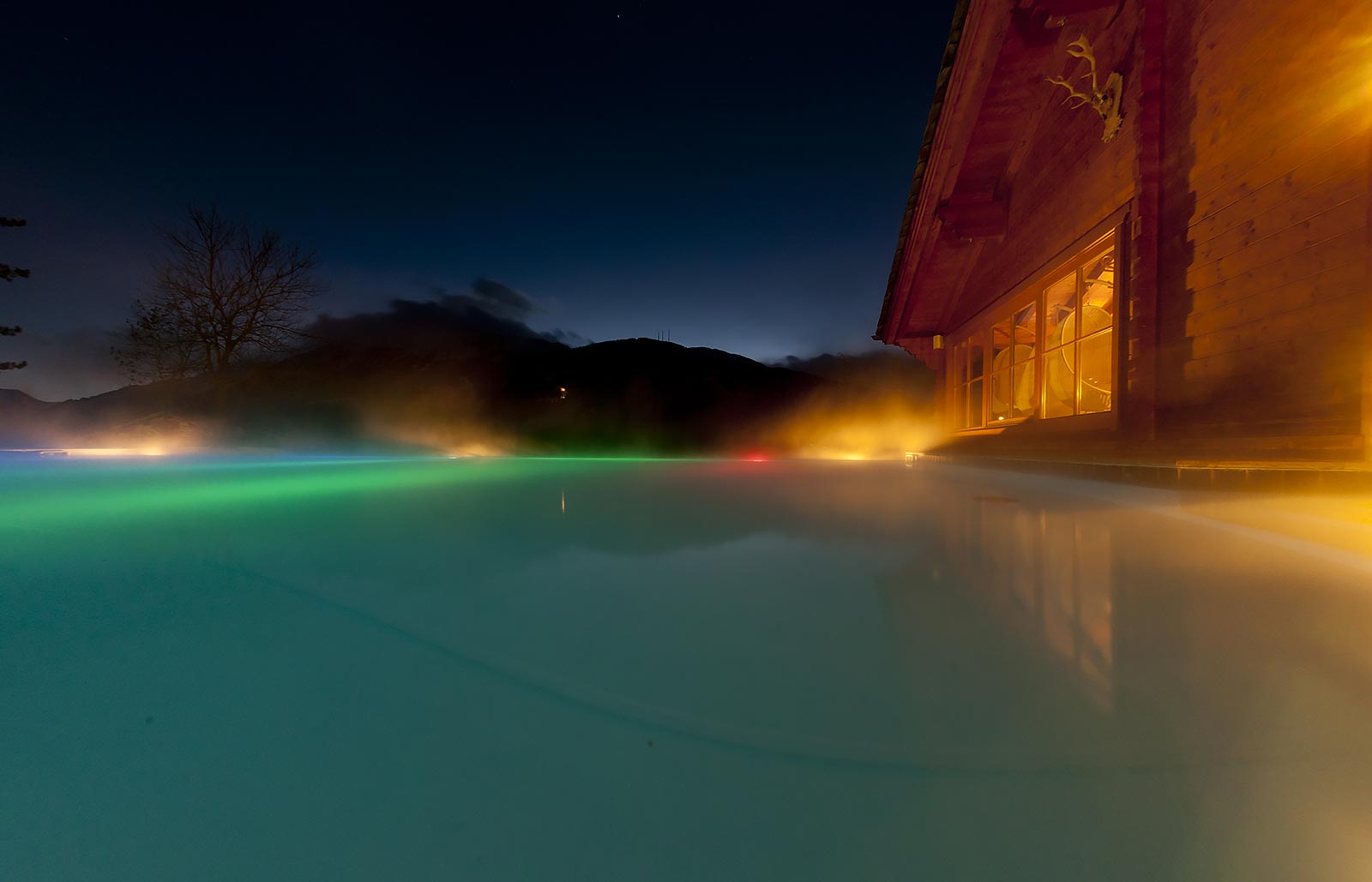 Hot water tub with lights on the outside of a wooden alpine house