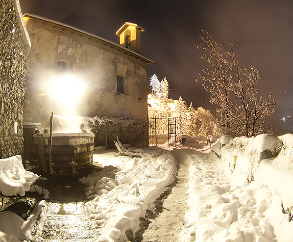 A snowy path with a house and a big wooden tub with warm water