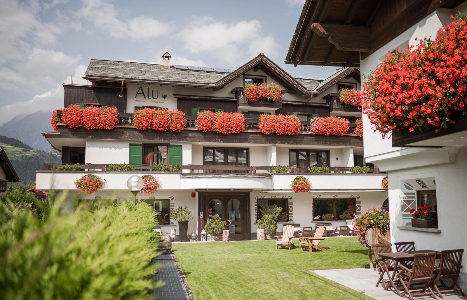 Angolo di salotto con poltrone in pelle e lampadario all'Hotel Alù a Bormio