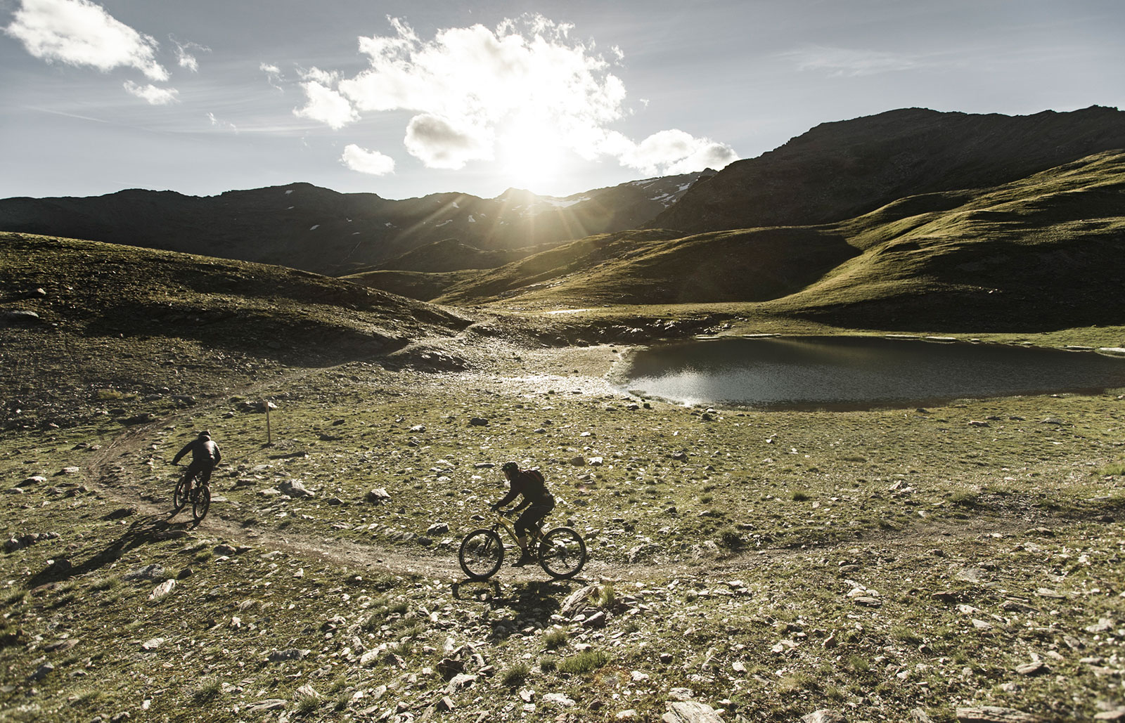 Two cyclists on a path next to a mountain lake
