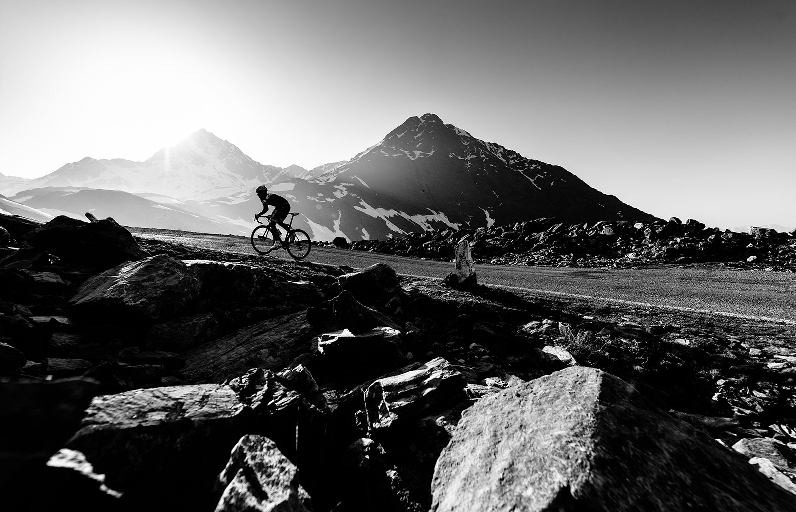 Un ciclista risale una strada di montagna tra le rocce