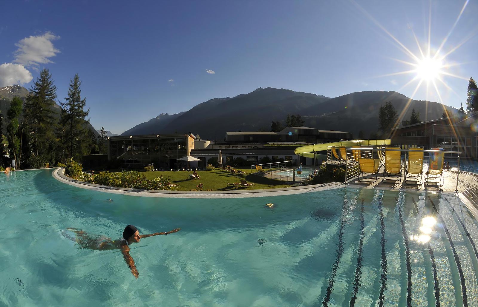 An exterior pool with a swimmer on a summer day